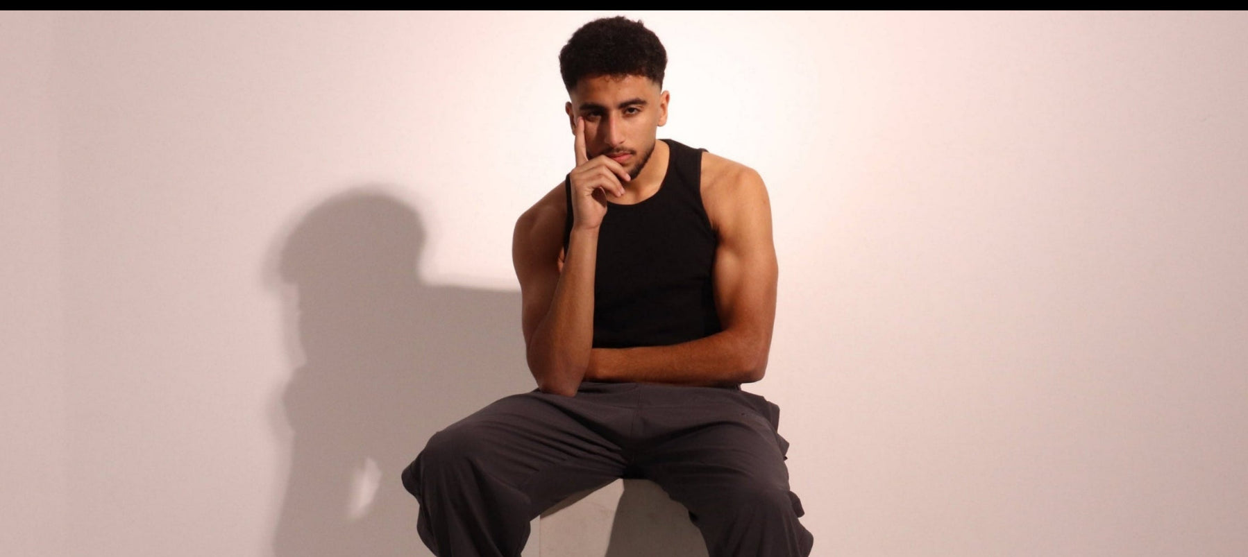 Man sitting against a white wall with a neutral expression